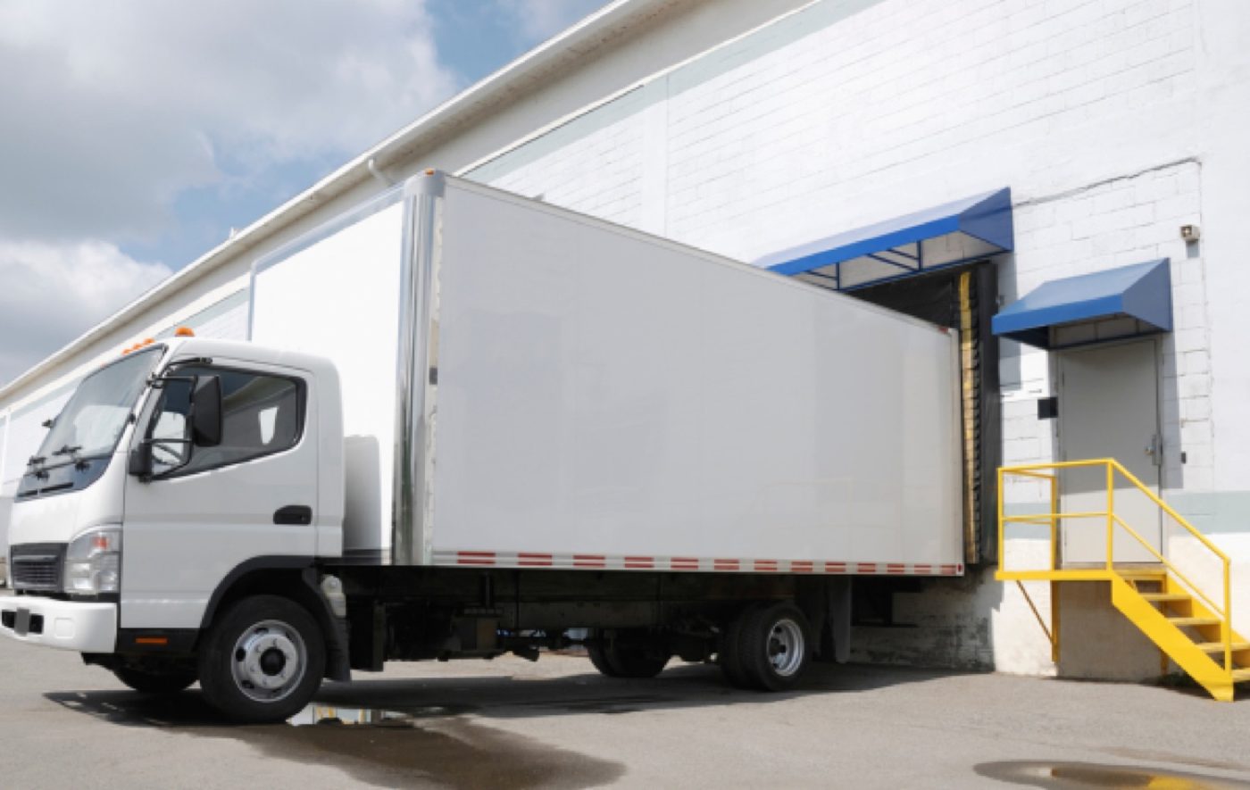 A refrigerated delivery truck backed into a loading dock