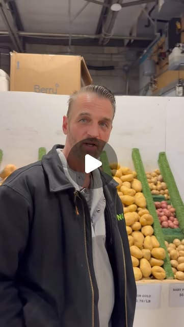 A member of the Aenos team in front of bins of potatoes at the Kaladar Market